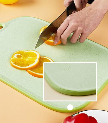 Hand slicing oranges on green cutting board with red bell pepper visible